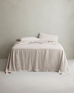 Natural linen sheet set with matching pillowcases from CULTIVER, neatly arranged on a bed with white bedding and soft natural lighting.