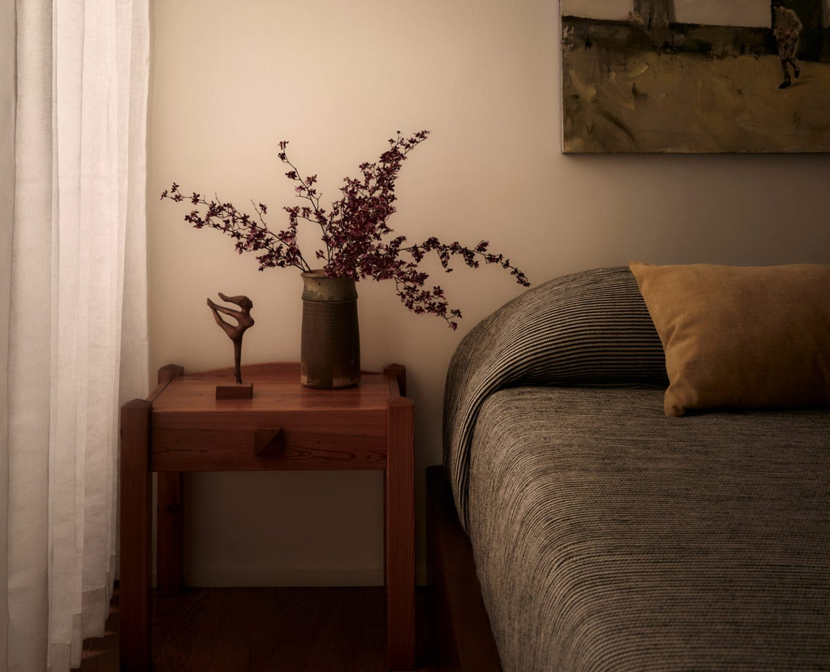 Nursery room with wooden nightstand, vase with flowers, and decorative items.
