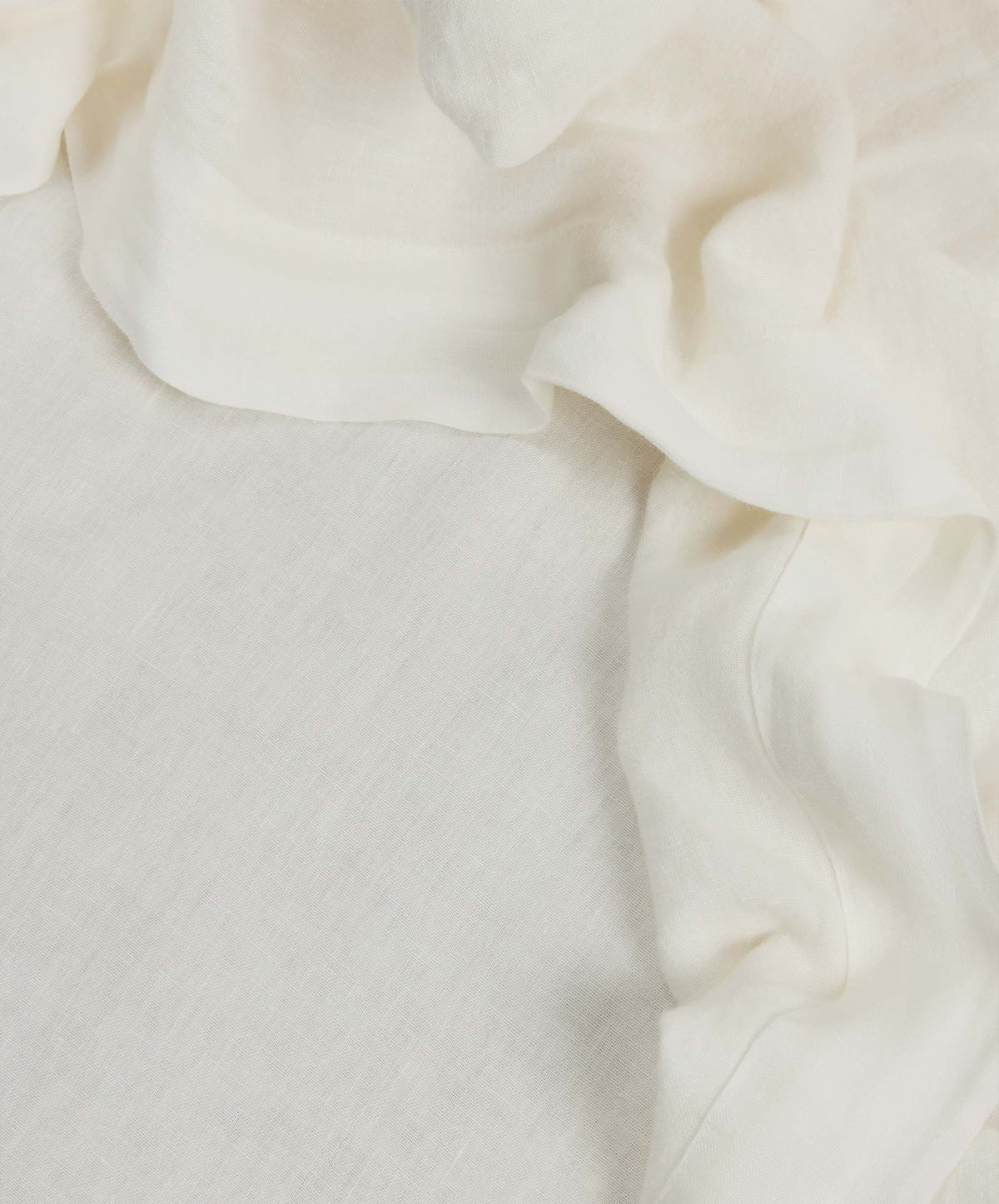 White, slightly crumpled fabric is draped along the top and right edges of the image, with a smoother, flat section of the same fabric filling the rest of the frame.