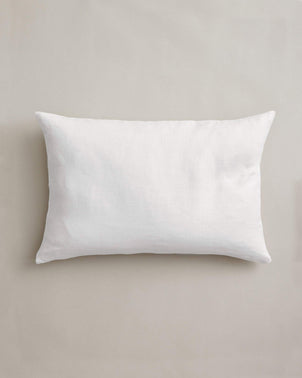 Centered on a light beige background is the Heavyweight Linen Rectangular Cushion Cover in White, crafted from heavyweight European flax linen and OEKO-TEX certified for safety.