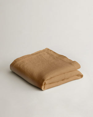 Folded heavyweight linen bedcover in sand color by CULTIVER, showcasing its textured fabric and relaxed, natural look.