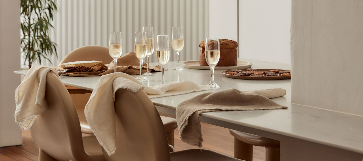 Dining table set with wine glasses, bread, and plates in a modern kitchen.