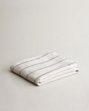 Folded CULTIVER Mira Linen Bedcover Ana, showcasing natural beige linen fabric with subtle texture and elegant design.