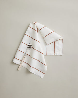 CULTIVER linen table napkin with Cedar Stripe pattern, soft fabric, neatly folded for elegant table setting.