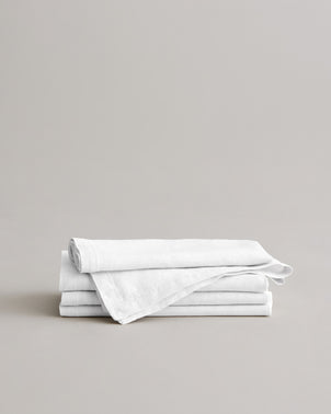 Stack of white CULTIVER linen table napkins on a clean surface, showcasing soft fabric and elegant table linen style.