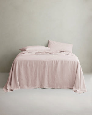 Soft blush linen sheet set with matching pillowcases on a bed, showcasing the breathable, luxurious bed linen from CULTIVER.