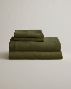 Folded CULTIVER linen sheet set with pillowcases in forest green, showcasing soft, natural bed linen fabric.