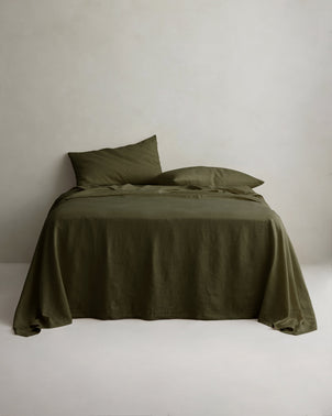 Linen sheet set with pillowcases in forest green, styled on a bed, by CULTIVER, showcasing soft, breathable bed linen.