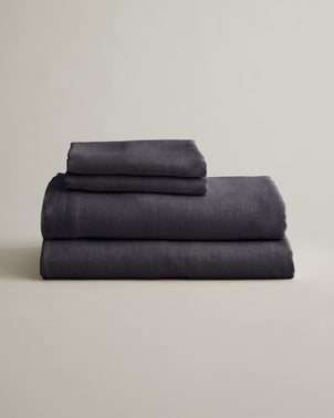 Folded slate linen sheet set with matching pillowcases from CULTIVER, showcasing soft, breathable bed linen for a stylish bedroom.