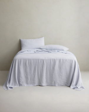 Sky-colored linen sheet set with pillowcases from CULTIVER styled on a bed for a cozy, elegant bedroom look.