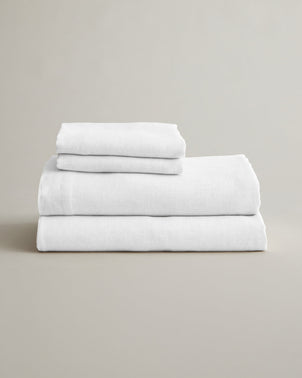 White linen sheet set with pillowcases from CULTIVER, neatly folded bed linen for a cozy, elegant bedroom look.