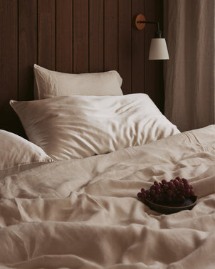 Ivory silk linen flip pillowcase by CULTIVER, showcasing smooth fabric and elegant design on a bed pillow.