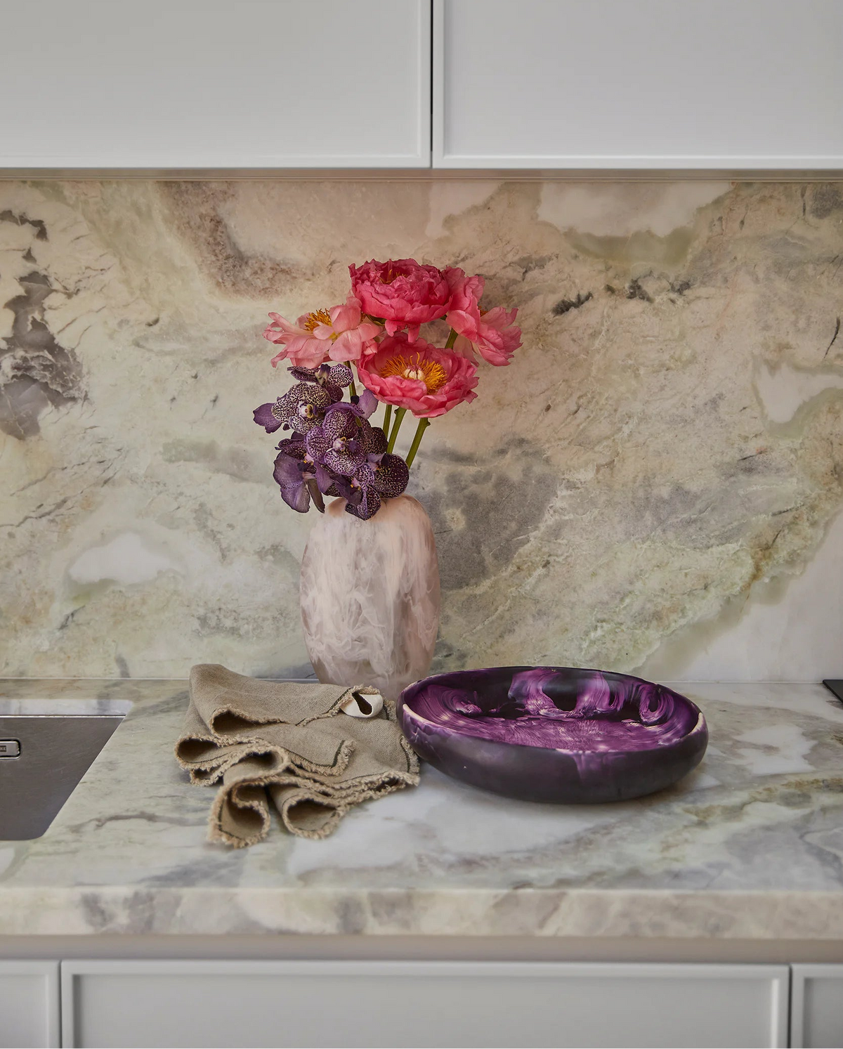 Decorative items on a kitchen counter with a marble backsplash